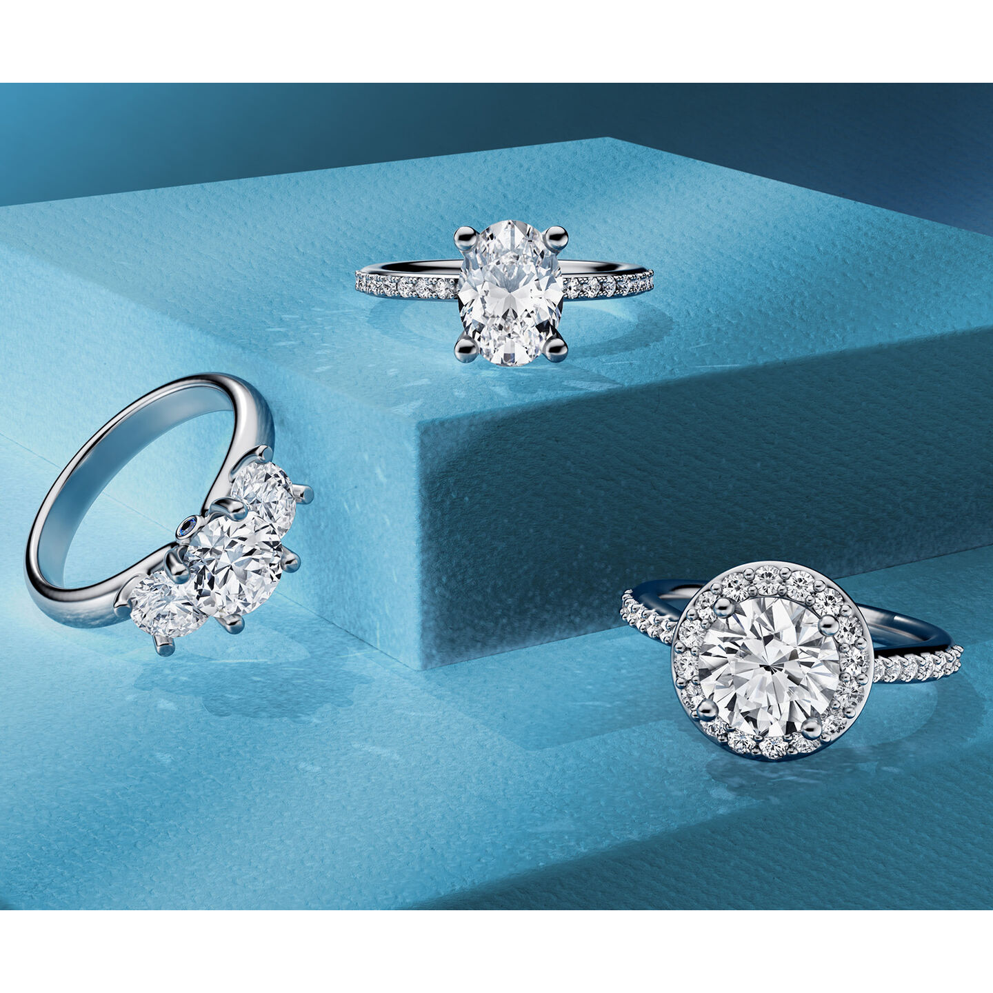 Three Birks diamond engagement rings on a blue background.